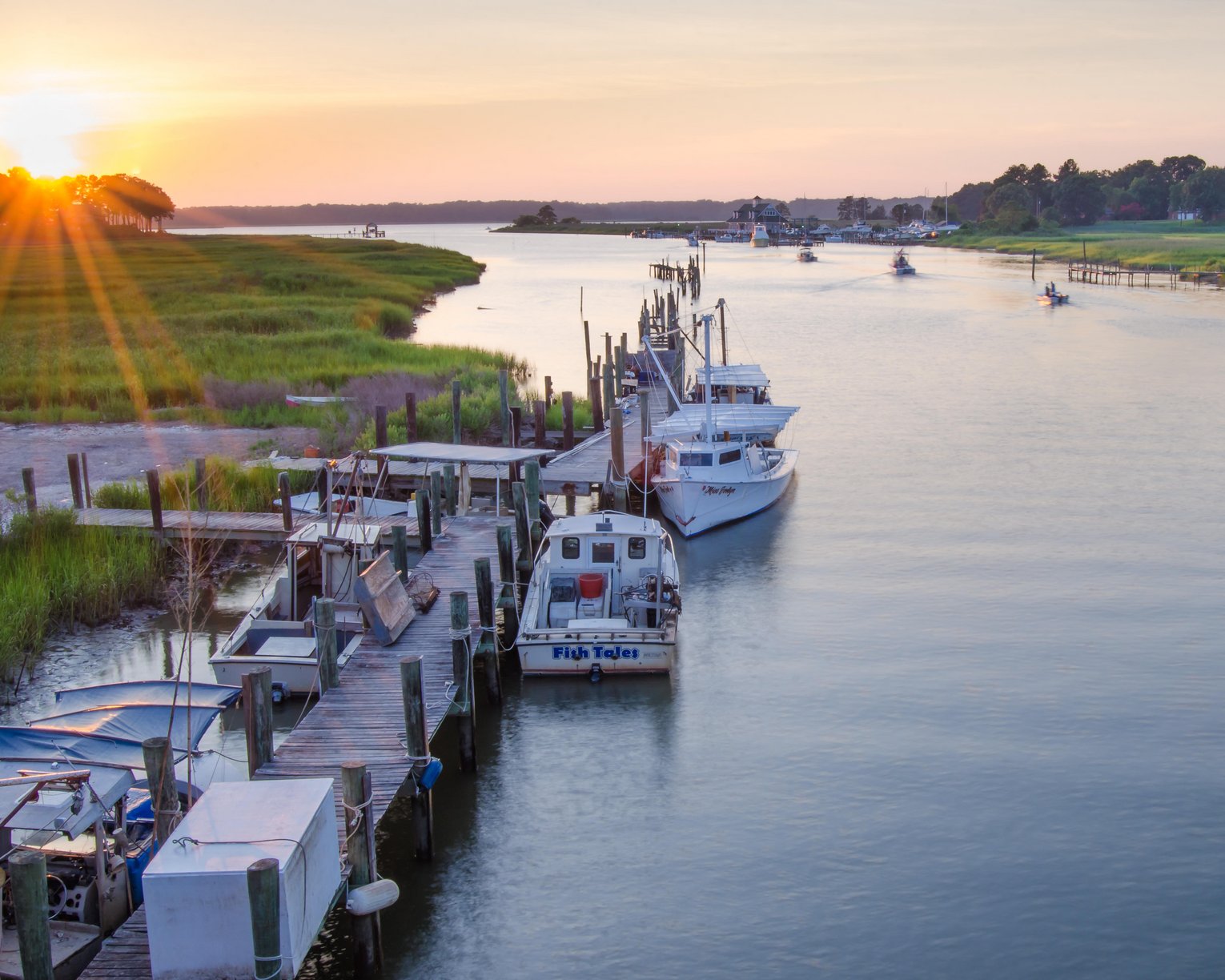 RJCT98 Fishing boats at a dock along a river at sunset in Isle of Wight County, Virginia